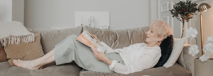 Femme senior lisant le magazine La Vie dans son canapé