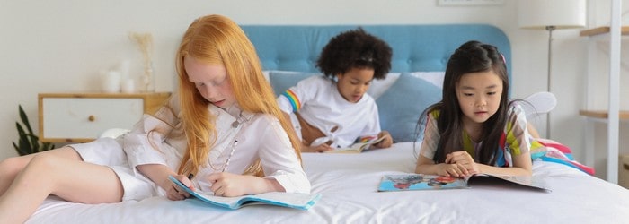 Trois jeunes filles lisant le magazine Manon sur un lit